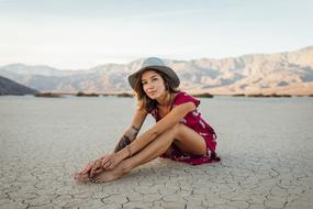 young attractive girl sits on ground at mountain landscape