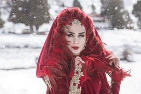 Portrait of the woman in red, decorated scarf and make-up, among the beautiful, snowy landscape in winter