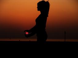 silhouette of long hair girl on beach at dusk