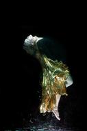 Woman in the beautiful and colorful dress, underwater, at black background