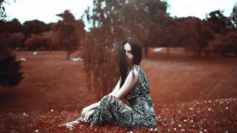 Beautiful Girl Sitting On grass at colorful nature background in Moscow