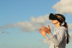 girl in virtual reality glasses against the blue sky