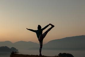 landscape of young girl doing Yoga exercise at scenic evening