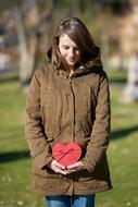 young girl holding red heart shape gift box outdoor