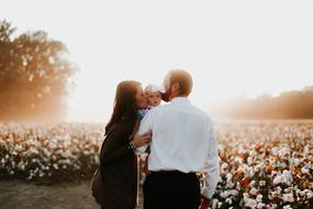 happy family, man and woman kissing baby outdoor