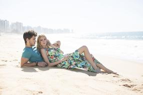 young couple rest on beach in view of city, Brazil
