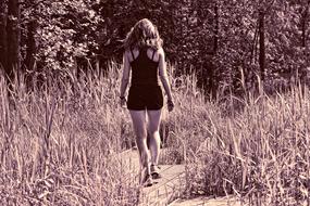 Retro photo with the back view of the woman, among the grass and trees