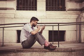 young man in Brown Leather Shoes looking at smartphone
