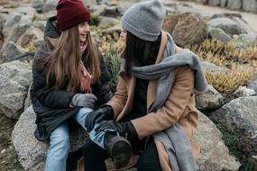 teen with mom sit on rocks in autumn