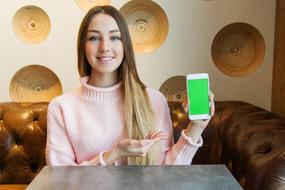 cheerful Young Girl with smartphone sits in front of Board at table