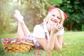 portrait of a woman lying on a grass with basket of apples