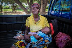 Smiling mother, with the son, near the trees, in Africa