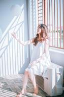 Girl in white dress, posing near the window with light