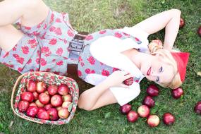 girl wearing a red riding hood with apples on the lawn
