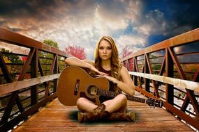 woman with guitar on wooden bridge