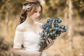 young beautiful asian girl in White dress with dry roses bouquet