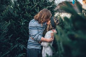 young Couple Kissing at fir tree