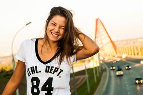 Portrait of the smiling, woman, near the beautiful bridge with cars, in sunlight