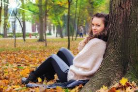 Portrait of the girl, lying down on the tree, among the beautiful and colorful trees in autumn