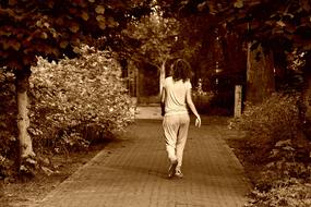 monochrome photo of a girl walking along the alley