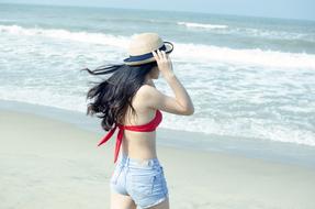 girl in bikini and denim shorts by the sea
