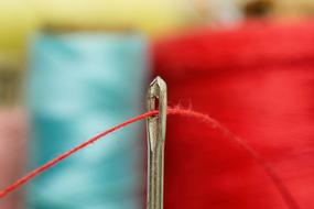 Close-up of the red thread inside the needle for sewing