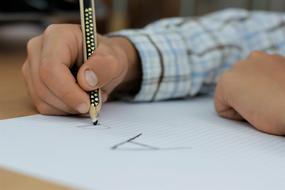 hands of child boy writing letter a on paper