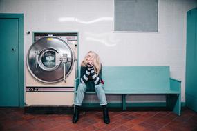 young Woman Sits on bench in laundry