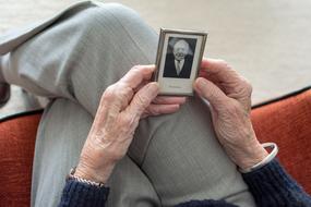 elderly man's hands hold a black and white photo