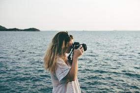 young girl taking photo at sea