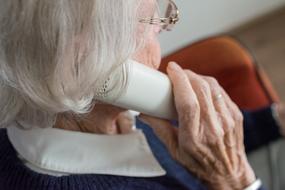 Old woman with glasses, talking on the telephone