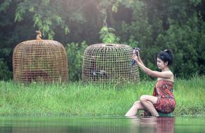 Girl in colorful dress, washing laundry in the river, among the beautiful green plants in Cambodia