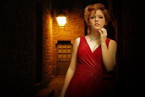 pretty Girl in red dress posing at aged wall