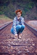 young Girl squatting down on railroad