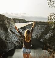 girl with a white flag near a mountain lake