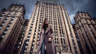 portrait of a girl in a raincoat near a multi-storey building