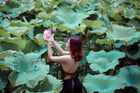 girl with flower among large green leaves