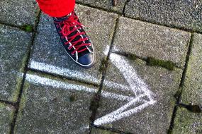 female Foot in Sneaker at arrow on pavement