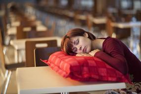 girl in red Sleeps on Pillow on table