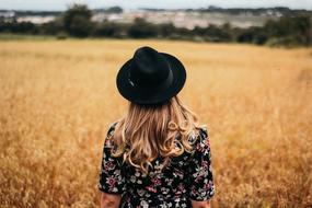 photo of a girl in a black hat on a cereal field