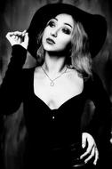 Black and white photo of the beautiful girl in the witch dress and hat, with the necklace