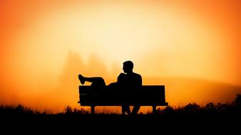 Silhouette of couple in love on bench at Sunset sky