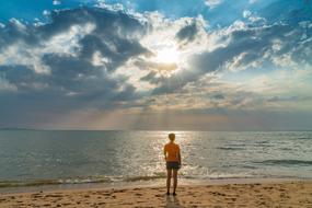 Woman looking at sunset on sea from Sand Beach