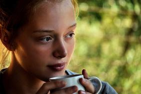 young girl with mug in hands outdoor
