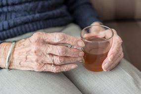 old woman hands holding tea cup