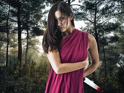 young Woman with bloody knife in hand at forest