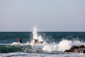 high water splashes at rocks in sea