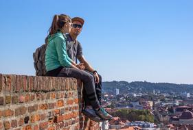 tourists sit on a brick wall