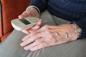 white telephone receiver in the hand of an elderly woman