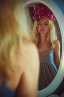 blonde with flowers on her head looks in the mirror